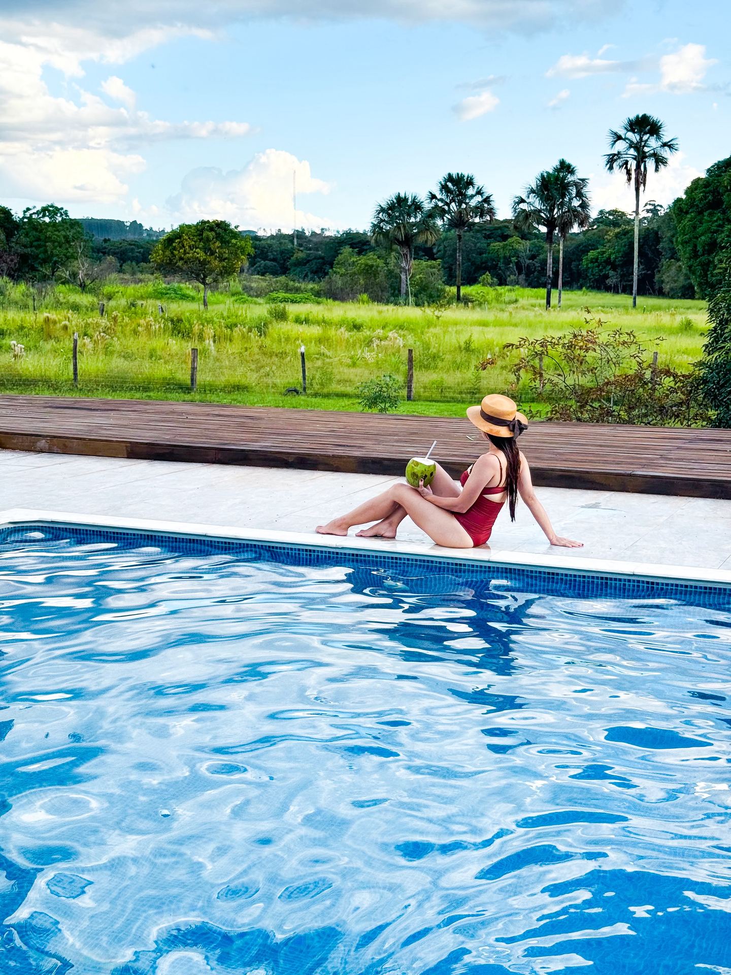 Hóspede relaxando na borda da piscina com água de coco