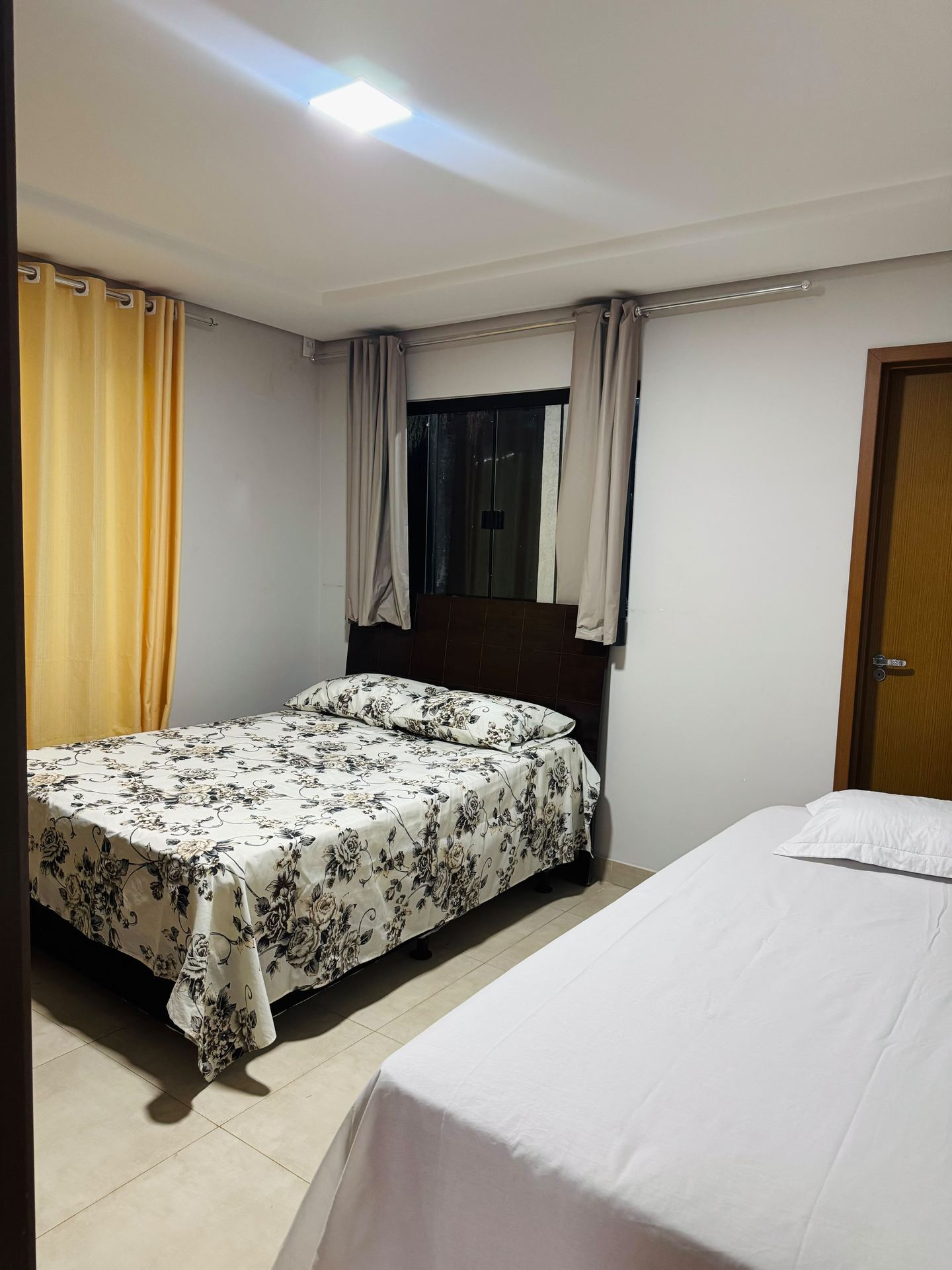 Quarto com cama de casal e cortina amarela